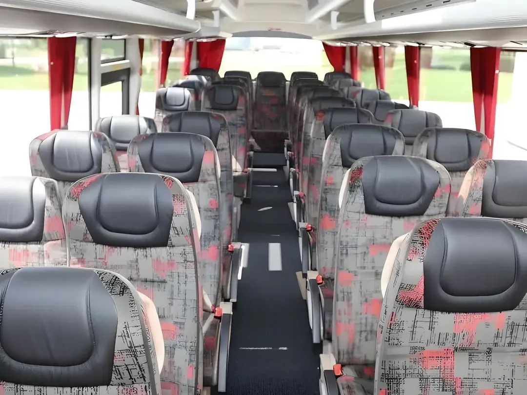 Coach interior with rows of fabric seats and red curtains