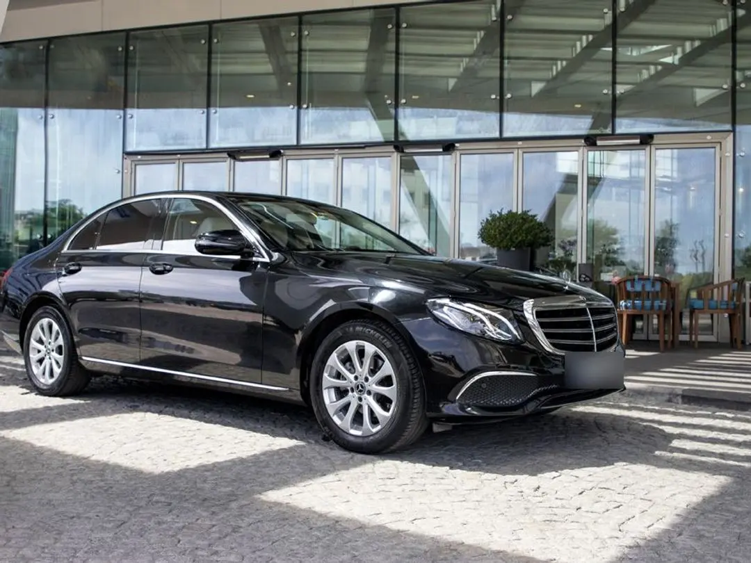 Black Mercedes-Benz E-Class sedan in front of a hotel entrance