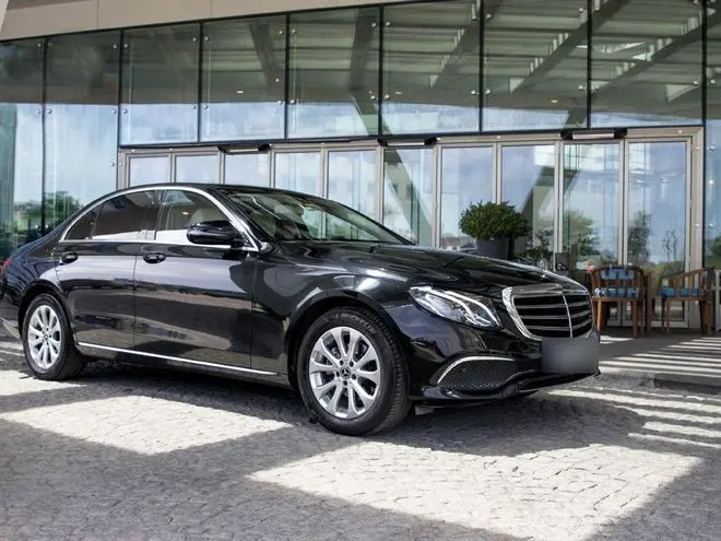 Black Mercedes-Benz E-Class sedan in front of a hotel entrance