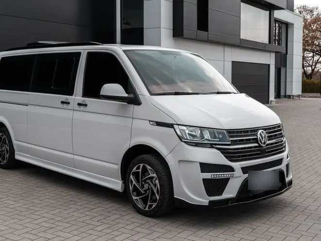 White Volkswagen Transporter minivan parked in front of a modern building