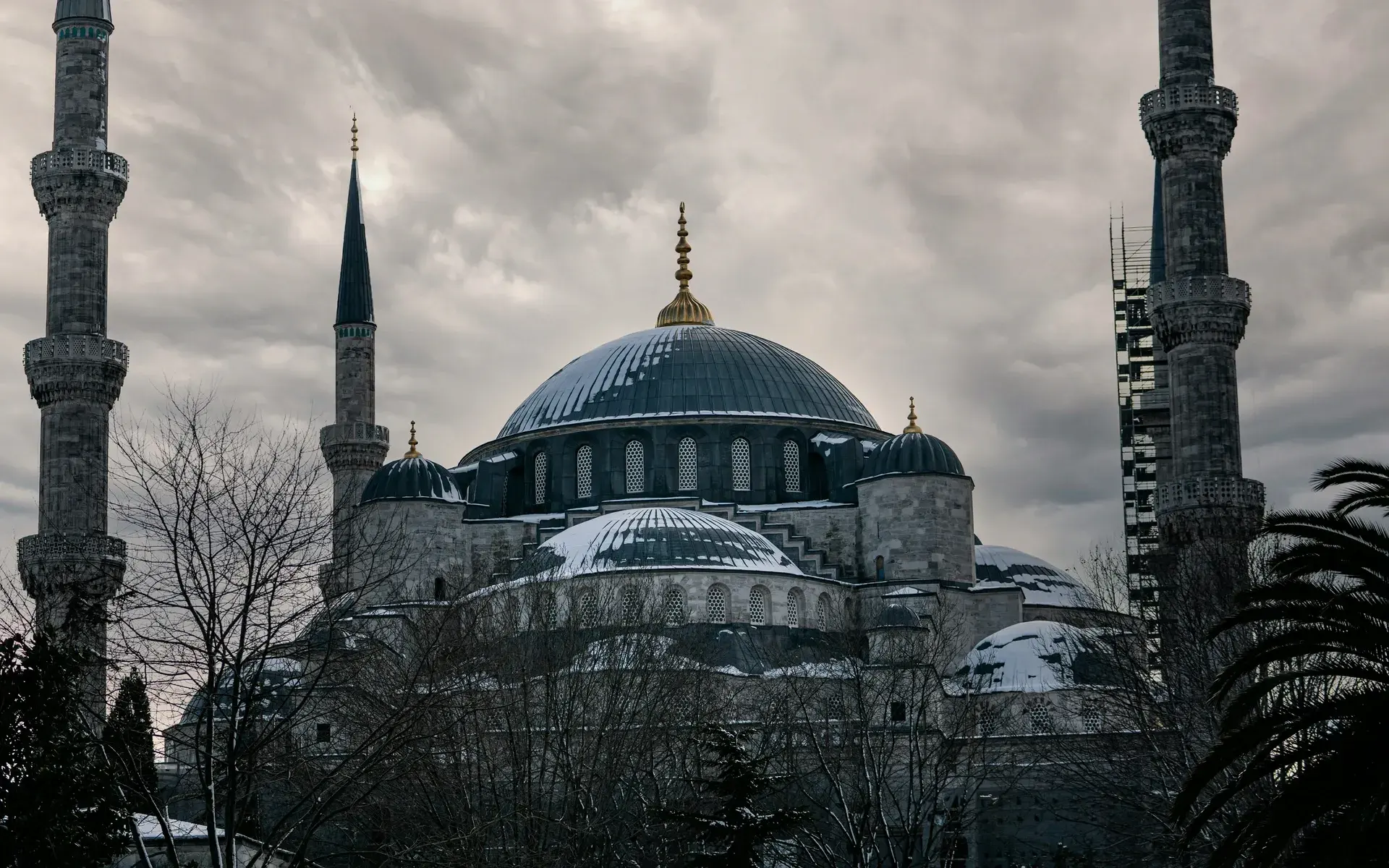 The Blue Mosque with snow on its domes under a dramatic winter sky
