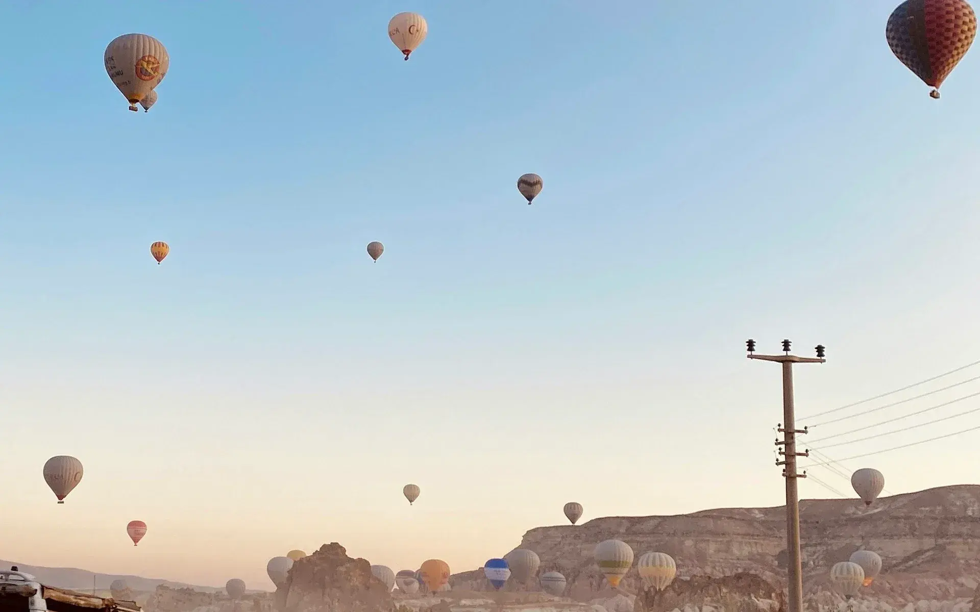 Hot air balloons scattered across the sky at first light