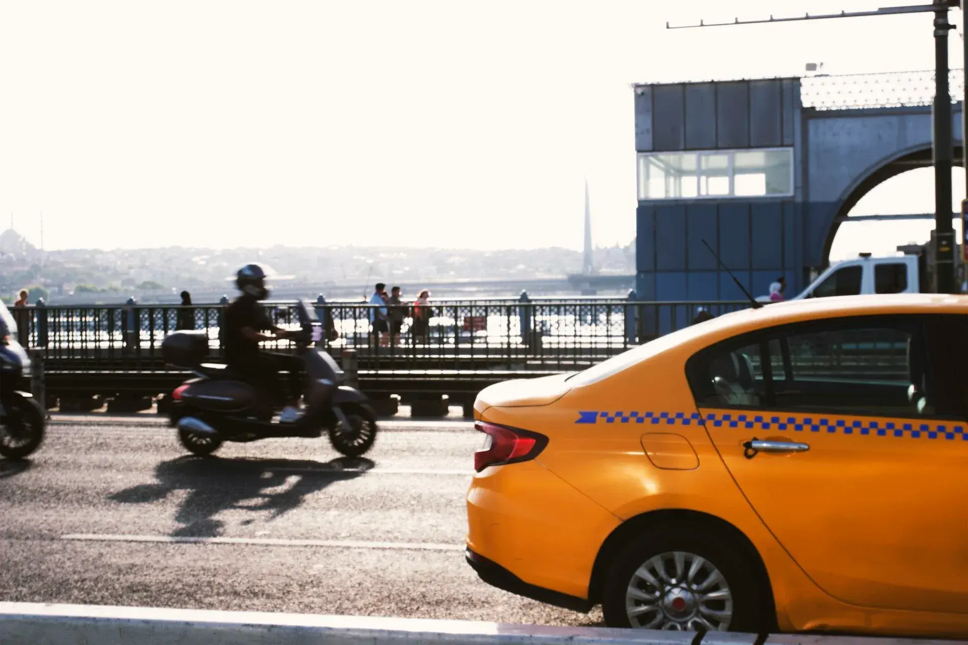 A yellow taxi crossing a bridge over the water in Istanbul