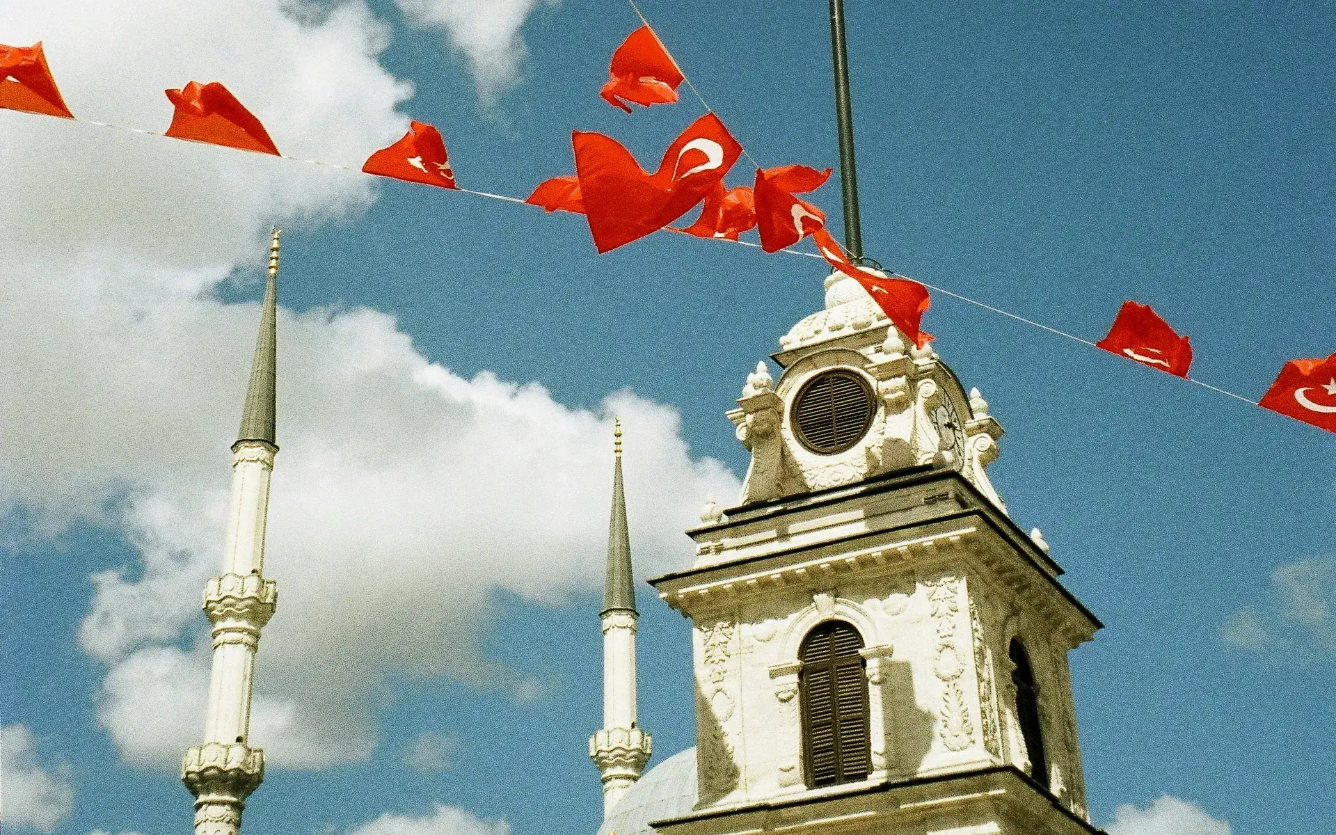 Strings of Turkish flags over an Ottoman clock tower and minarets in Istanbul