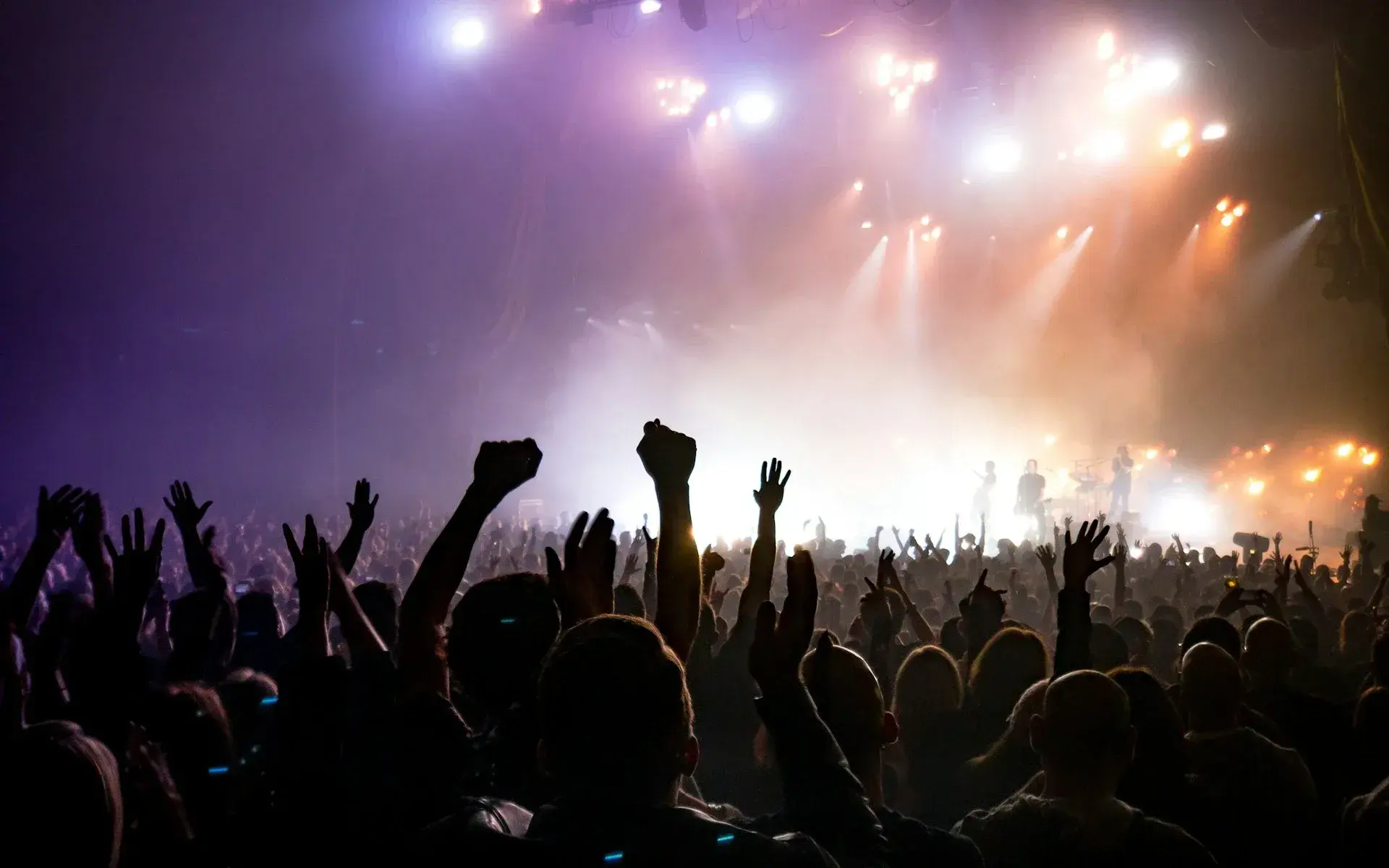 Crowd with raised hands in front of a lit festival stage