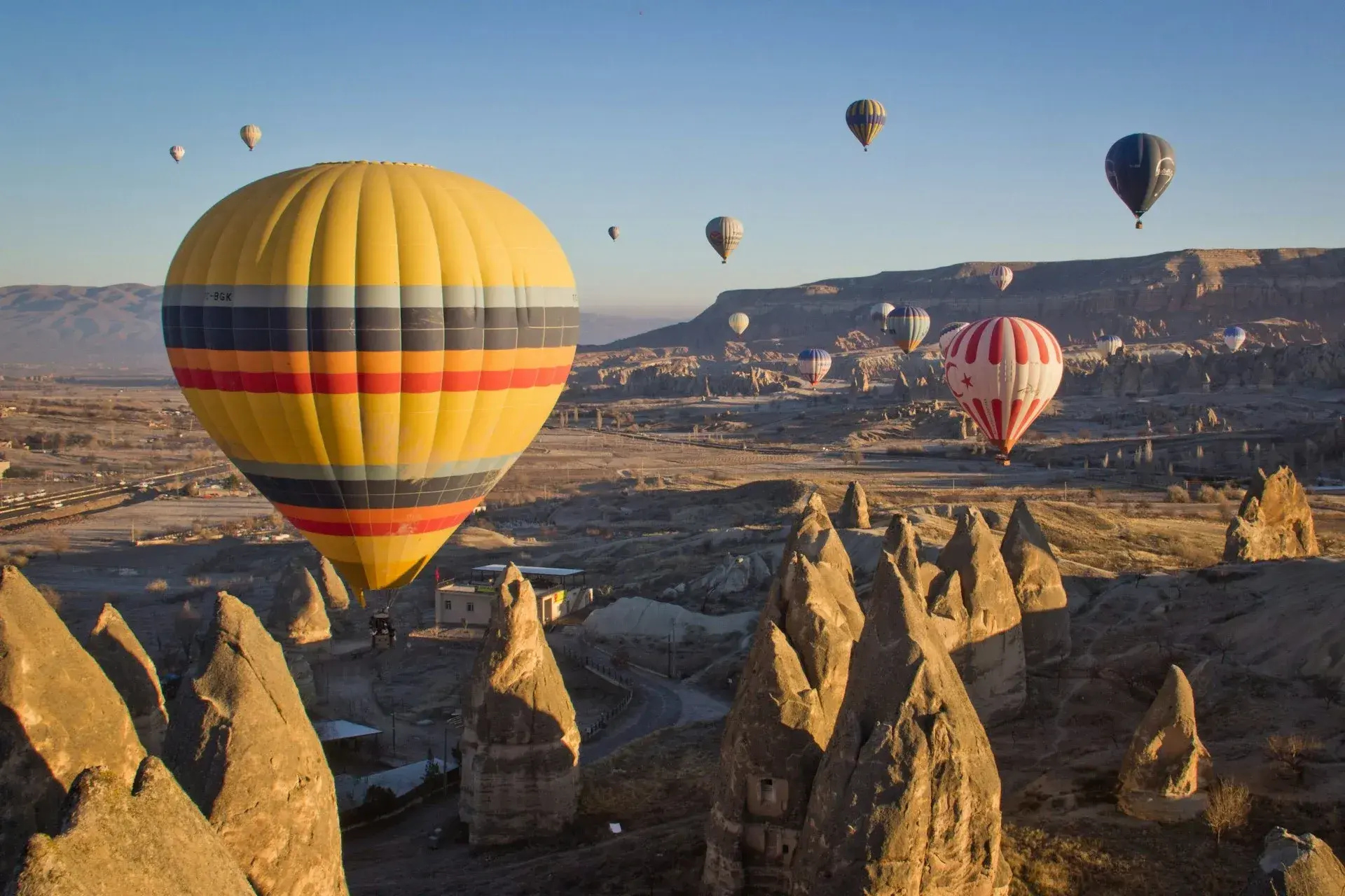 Heißluftballons steigen bei Sonnenaufgang über den Feenkaminen Kappadokiens auf