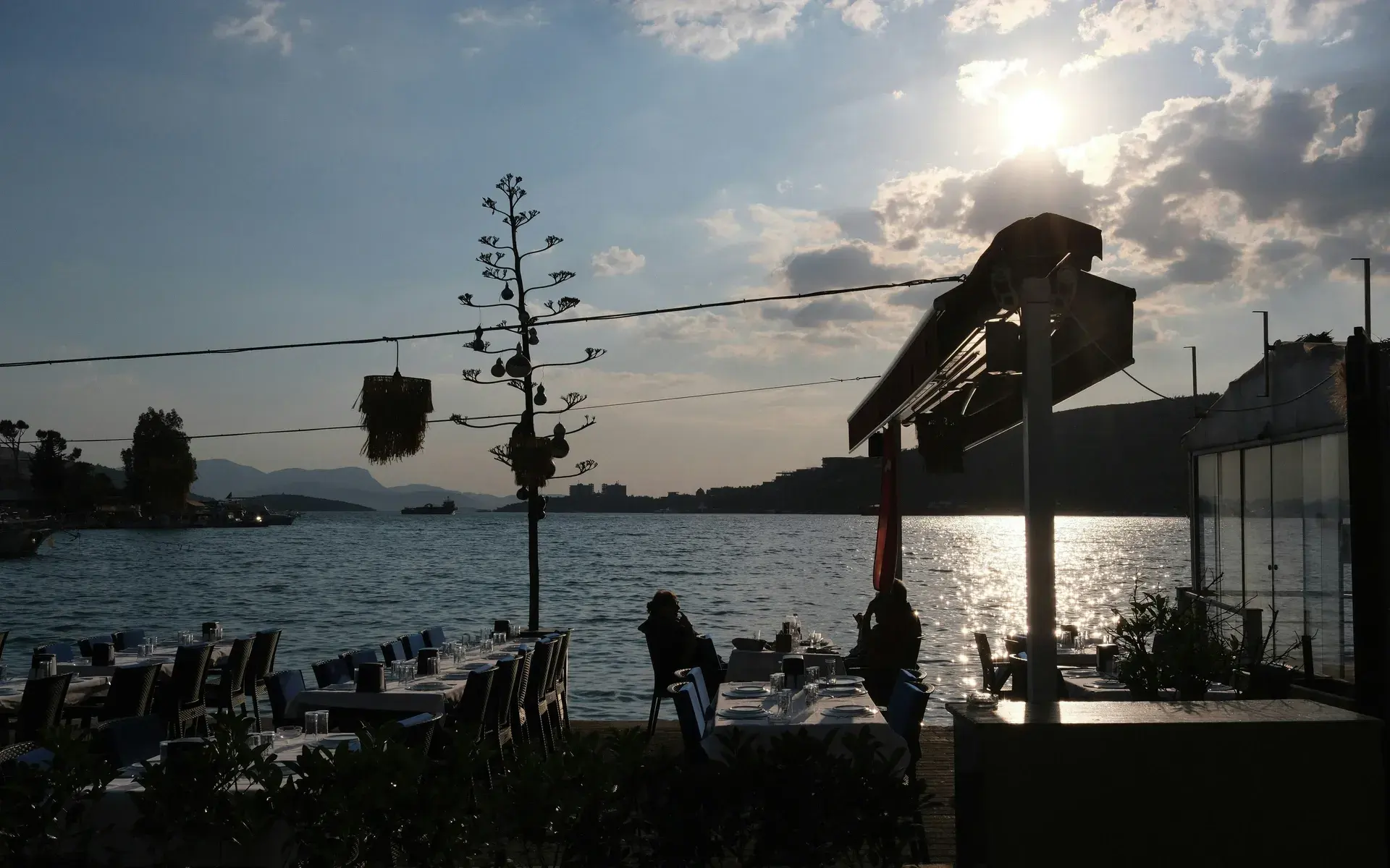 Restaurant tables at the water's edge on the Bodrum peninsula as the sun sets