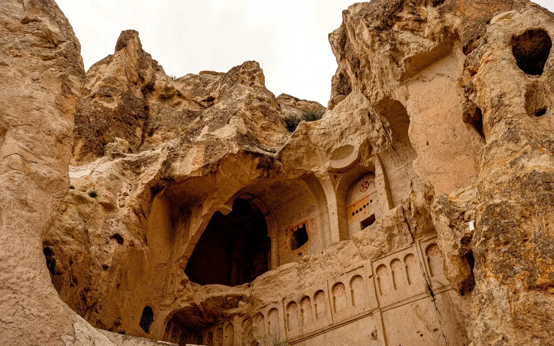 A façade carved into the soft volcanic rock of Cappadocia, with arched niches and windows