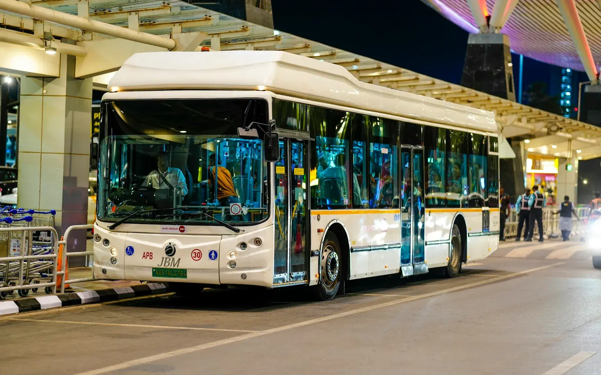 Shuttle bus waiting at a lit airport terminal at night
