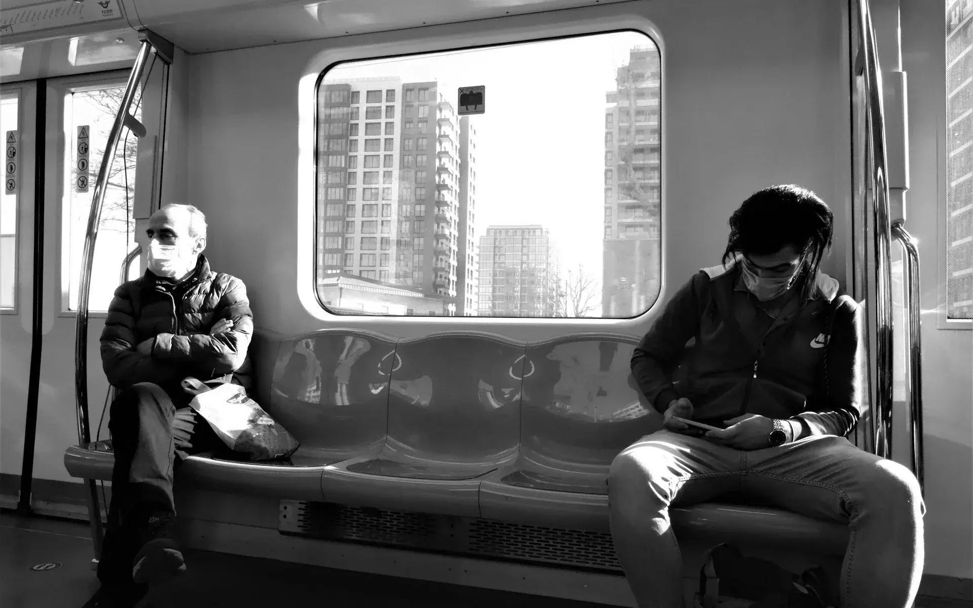 Passengers sitting in a metro car with the city passing outside
